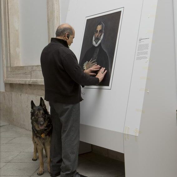 Courtesy of Museo del Prado.

A blind patron feels a painting at a touchable exhibit with their service dog.
